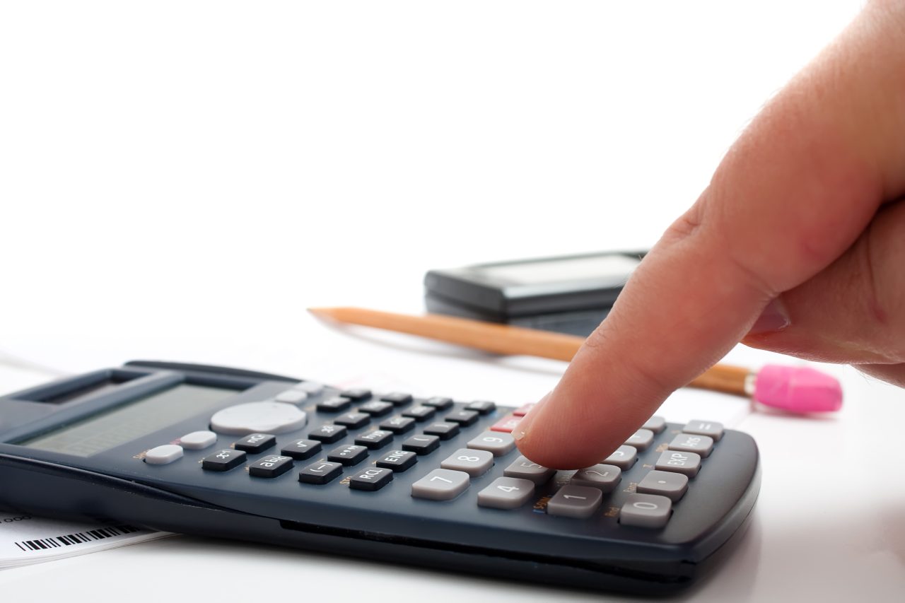A finger adding up figures using a calculator isolated over a white background.